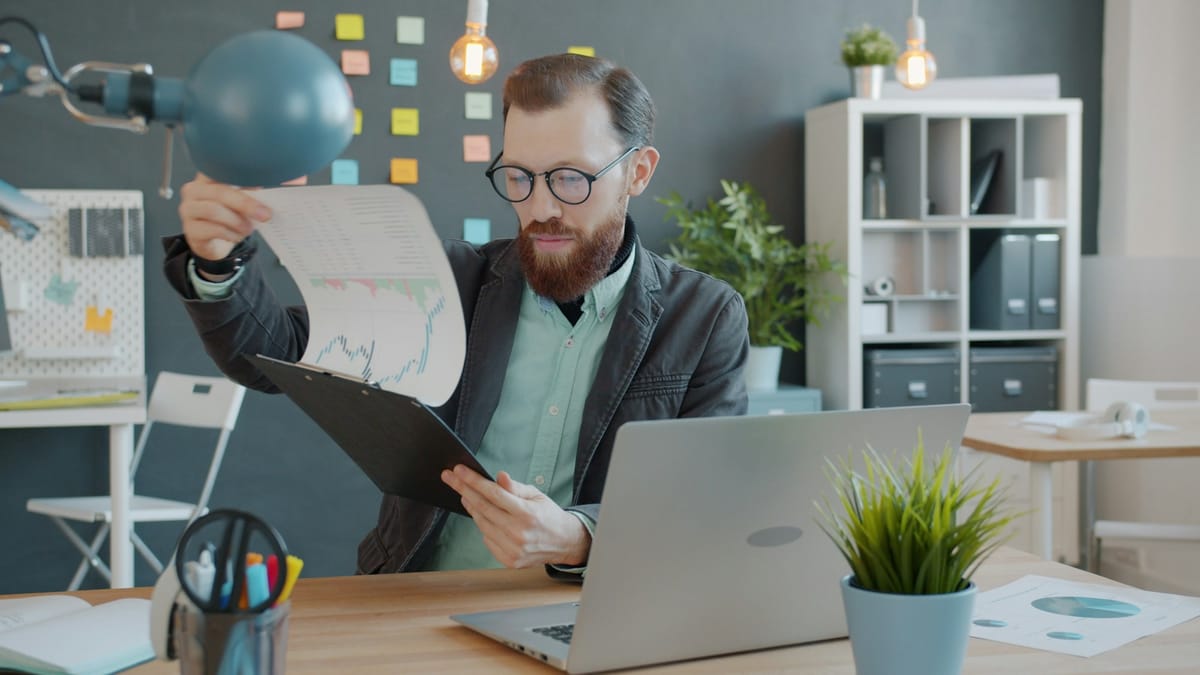 A man at an office desk reviewing printed documents