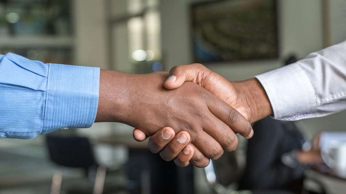 Two people shaking hands across a desk after agreeing a job offer